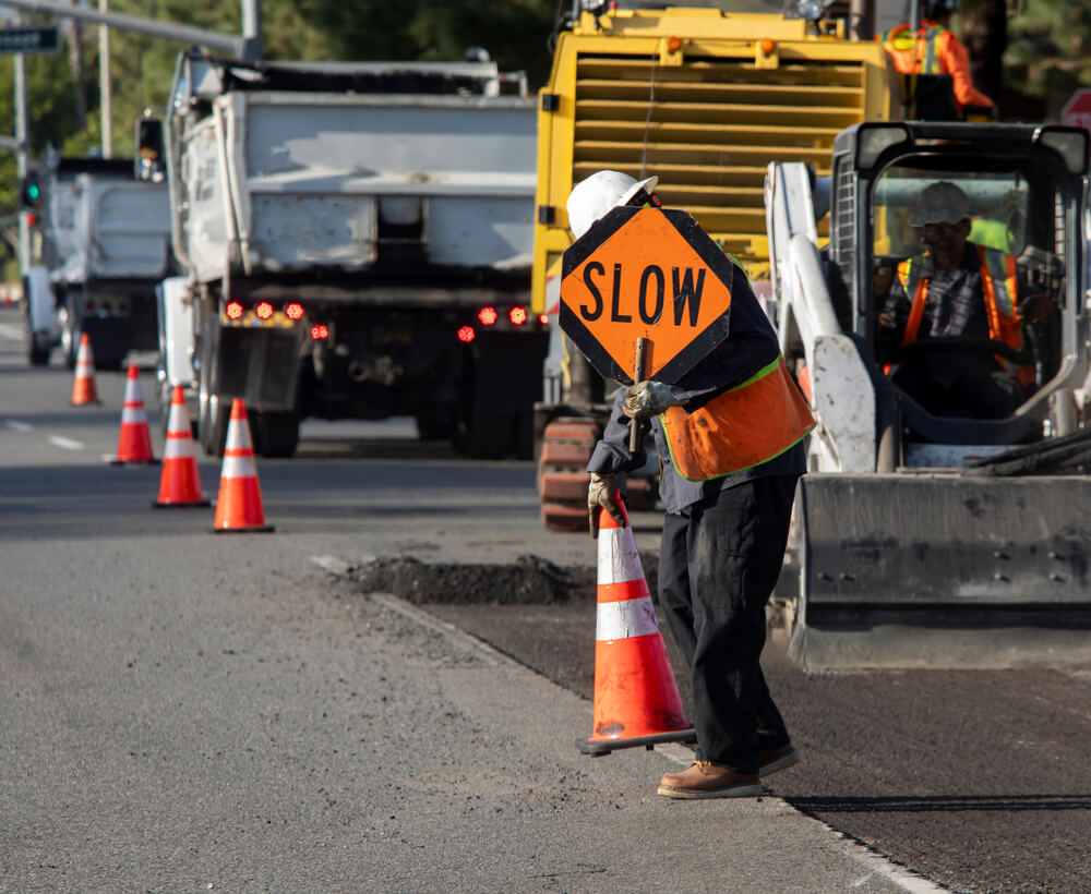 Construction worker in the street putting slow caution sign.