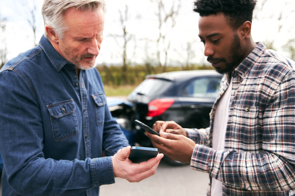 Drivers in car accident exchanging contact details for insurance.