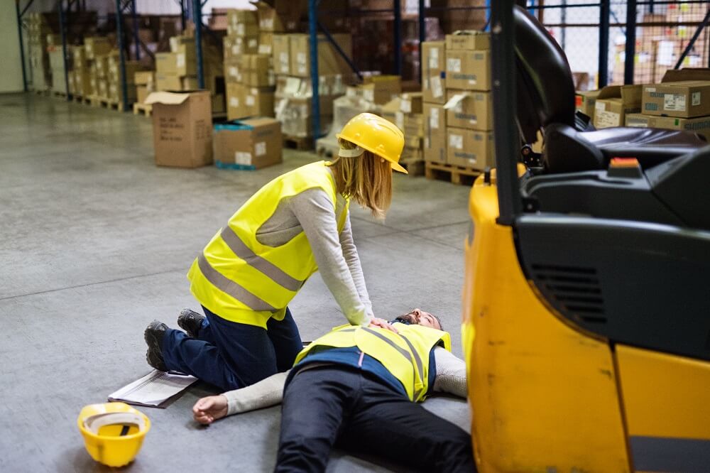 Female warehouse employee helping injured coworker.