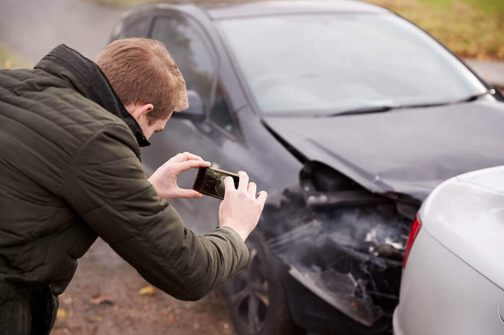 Driver taking photo of the car damage in an accident.